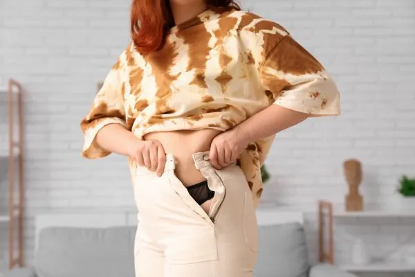 Image of woman trying to do her trousers up after pregnancy weight gain Kent